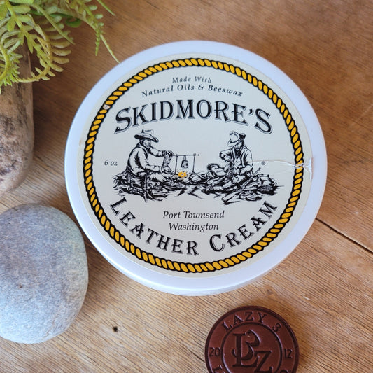 Skidmore's Leather Cream container on a wooden surface with a coin for scale.
