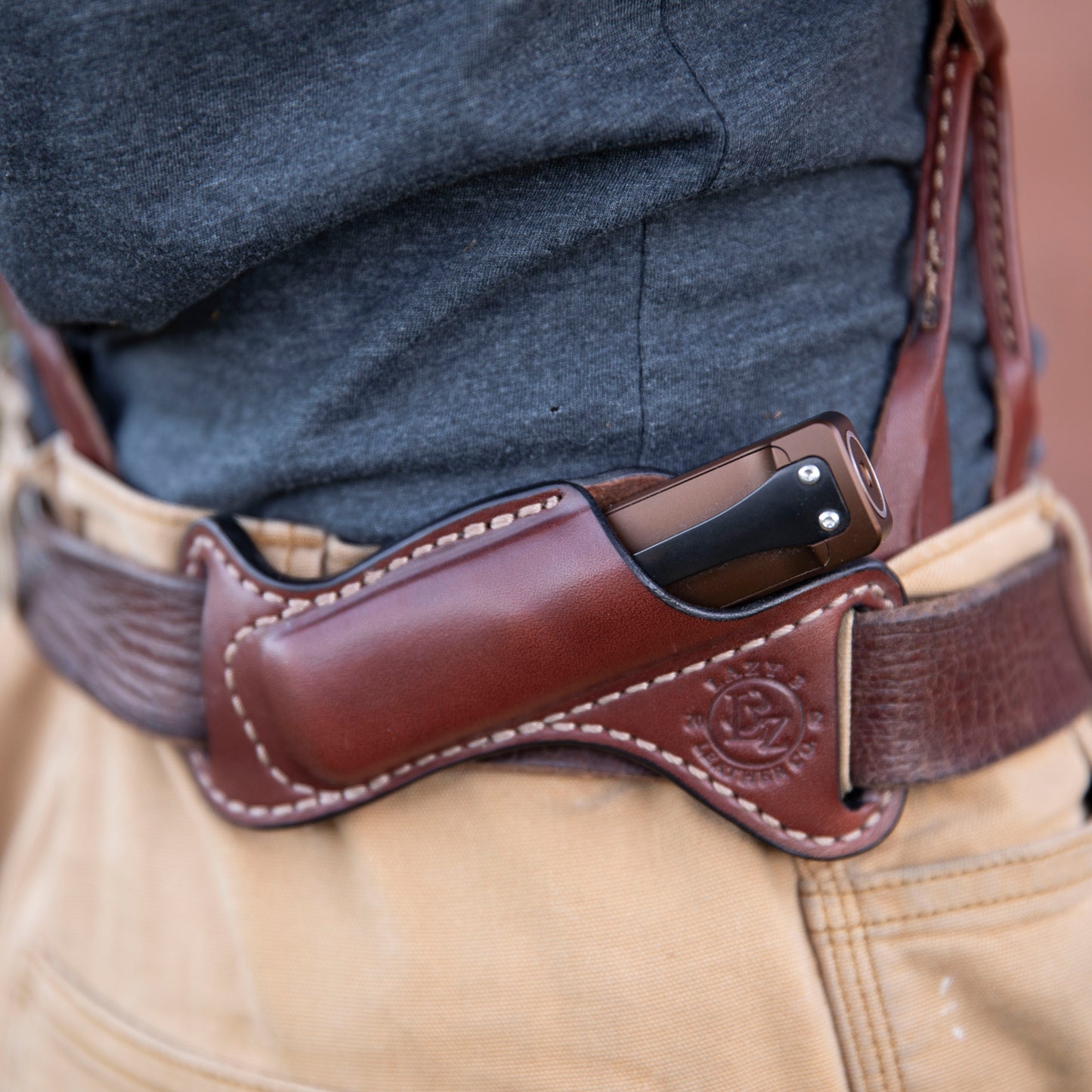 Brown leather flashlight in holster worn on a person's belt at the waist.