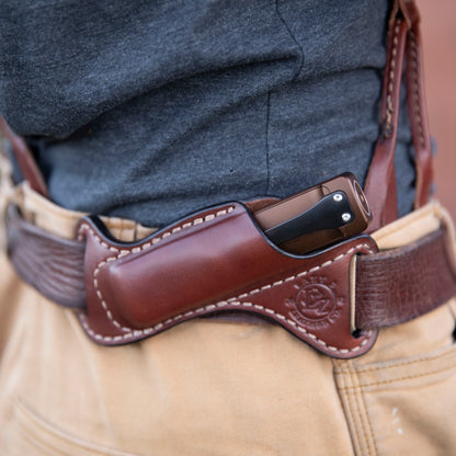 Brown leather flashlight in holster worn on a person's belt at the waist.