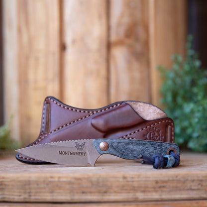 Benchmade Dacian Bishop Scout Carry sheath in brown leather, displayed behind the knife on a wooden background