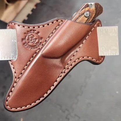 55 Scout Leather sheath with knife holstered mounted on a ruler during the drying process made by Lazy 3 Leather Co