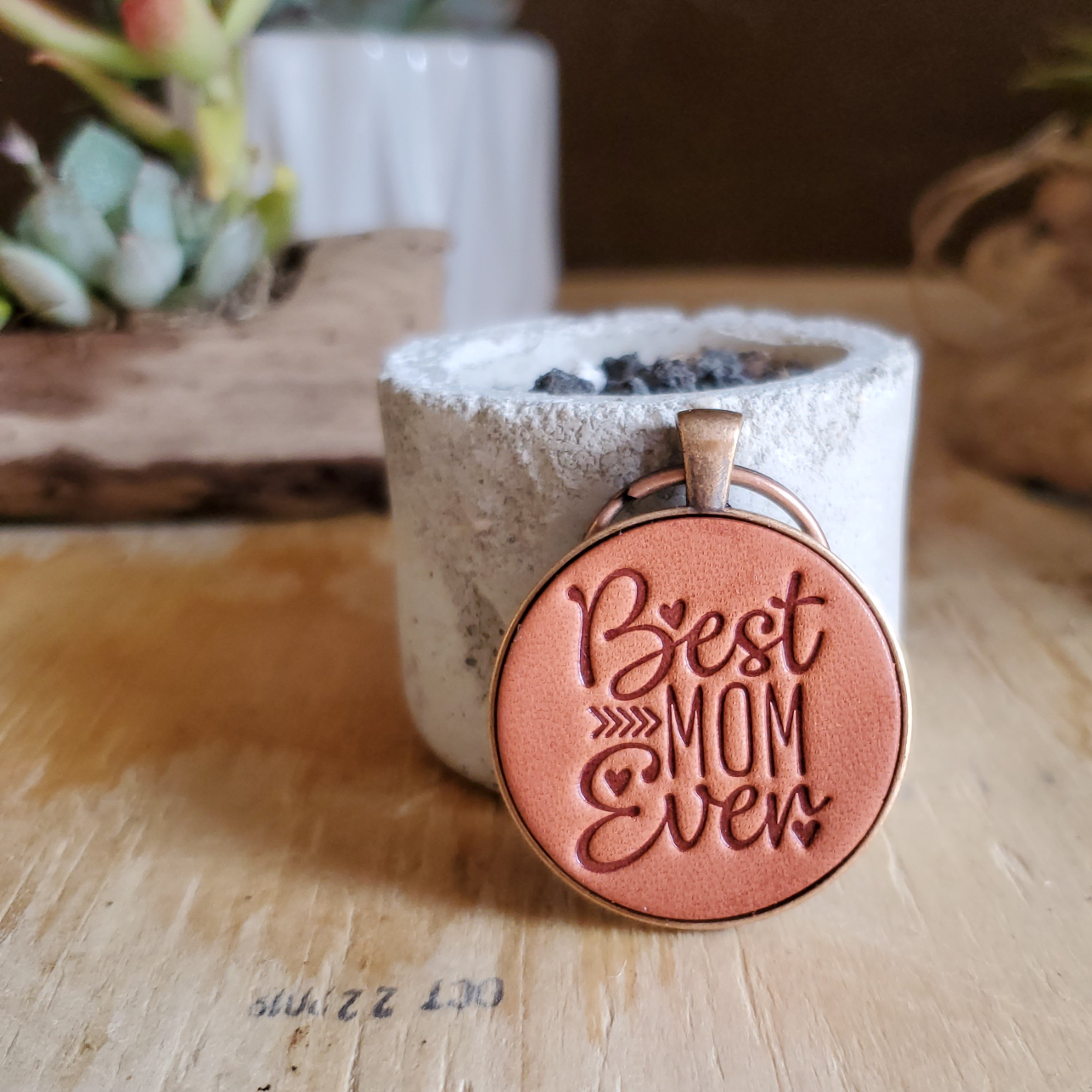 Hand stamped leather keychain that says Best Mom Ever that has been mounted in a round metal pendant with a 1 inch antique copper keyring. This keychain is made using veg tanned Wickett & Craig leather.