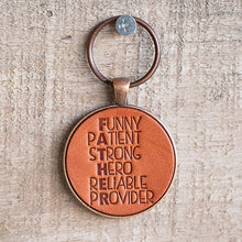 Load image into Gallery viewer, Hanging leather keychain. Hand stamped leather keychain that says Funny, patient, strong, hero, reliable and provided. The letters that spell out FATHER are in bold. The stamped leather has been mounted in a round metal pendant with a 1 inch antique copper keyring. This keychain is made using veg tanned Wickett &amp; Craig leather.